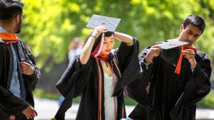 three students outside wearing cap and gown